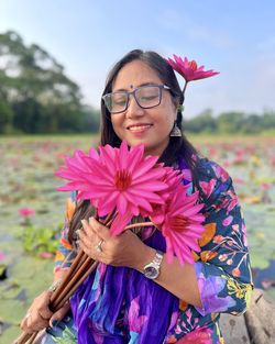 Portrait of smiling young woman holding yellow flower