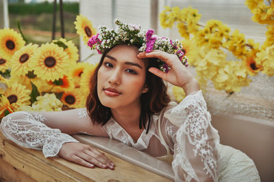 Portrait of beautiful young woman sitting by potted plant