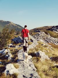 Rear view of man standing on rock against sky