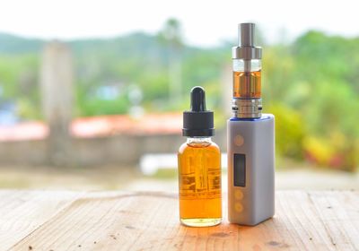 Essential oil in bottle by electronic cigarette on table