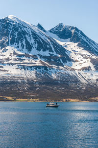 Scenic view of sea and snowcapped mountains against sky