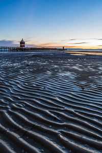 Sunrise over the sea. the lighthouse of lignano sabbiadoro and the games of sand and colors. italy