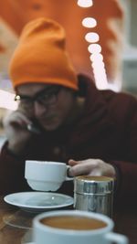 Close-up of young man talking over smart phone while having coffee in cafe