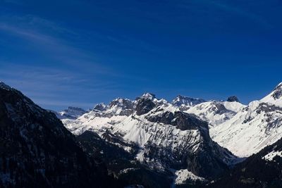 Scenic view of snowcapped mountains against blue sky