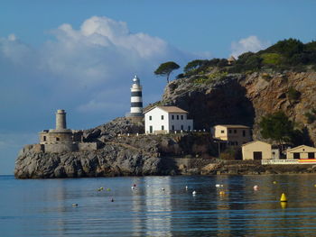 Buildings ad lighthouse by sea against sky