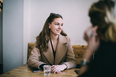Portrait of a smiling young woman sitting on table