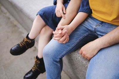 Young couple holding hands while sitting together on wall