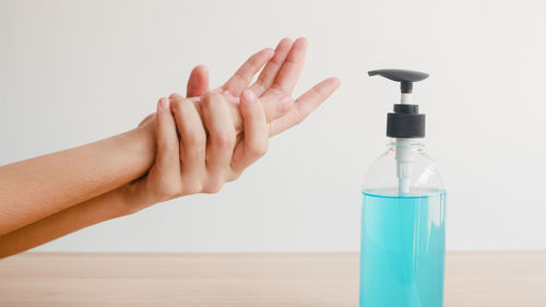 Close-up of woman hand on table against white background