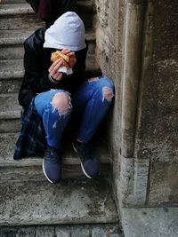 Midsection of woman sitting on staircase against wall