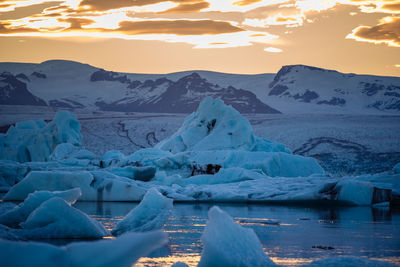 Scenic view of icebergs on lake against sky during sunset