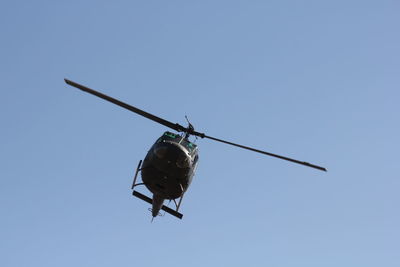 Low angle view of helicopter flying against clear blue sky