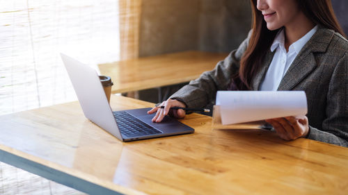 Midsection of woman using laptop on table