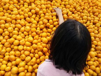 Rea view of woman picking yellow fruits in market