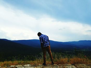 Rear view of man standing on landscape against sky