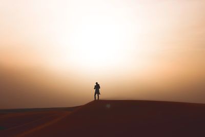 Silhouette woman standing on desert against clear sky