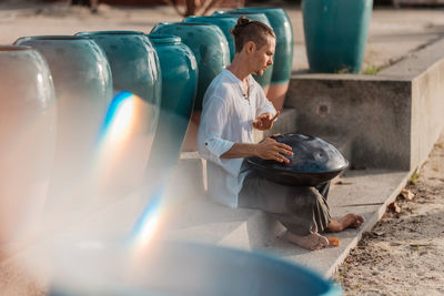 A man sits on the beach and plays the glucophone