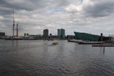 Buildings by river against sky in city