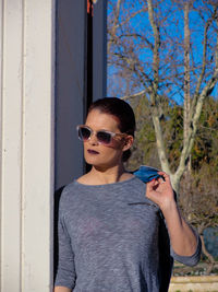 Portrait of young woman standing against wall