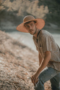 Portrait of young man wearing hat while standing on land