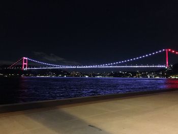 Illuminated golden gate bridge over sea against sky at night