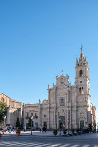 Group of people in front of building against clear blue sky