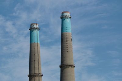 Low angle view of smoke stacks against sky