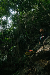 Man sitting on rock in forest