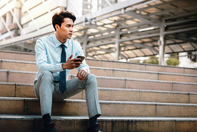 Full length of young man sitting on staircase