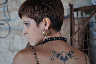 Rear view of thoughtful female hipster with tattoo on back