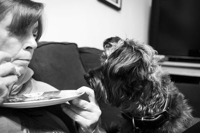 Close-up of woman eating with dog at home