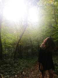 Man standing by tree in forest