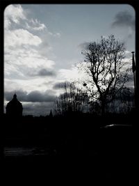 Bare trees against cloudy sky