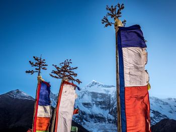 Low angle view of flags against clear blue sky