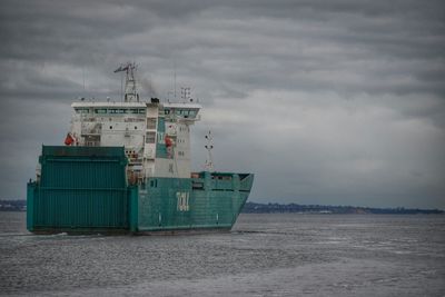 Ship in sea against cloudy sky