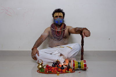 Full length portrait of young man sitting on wall