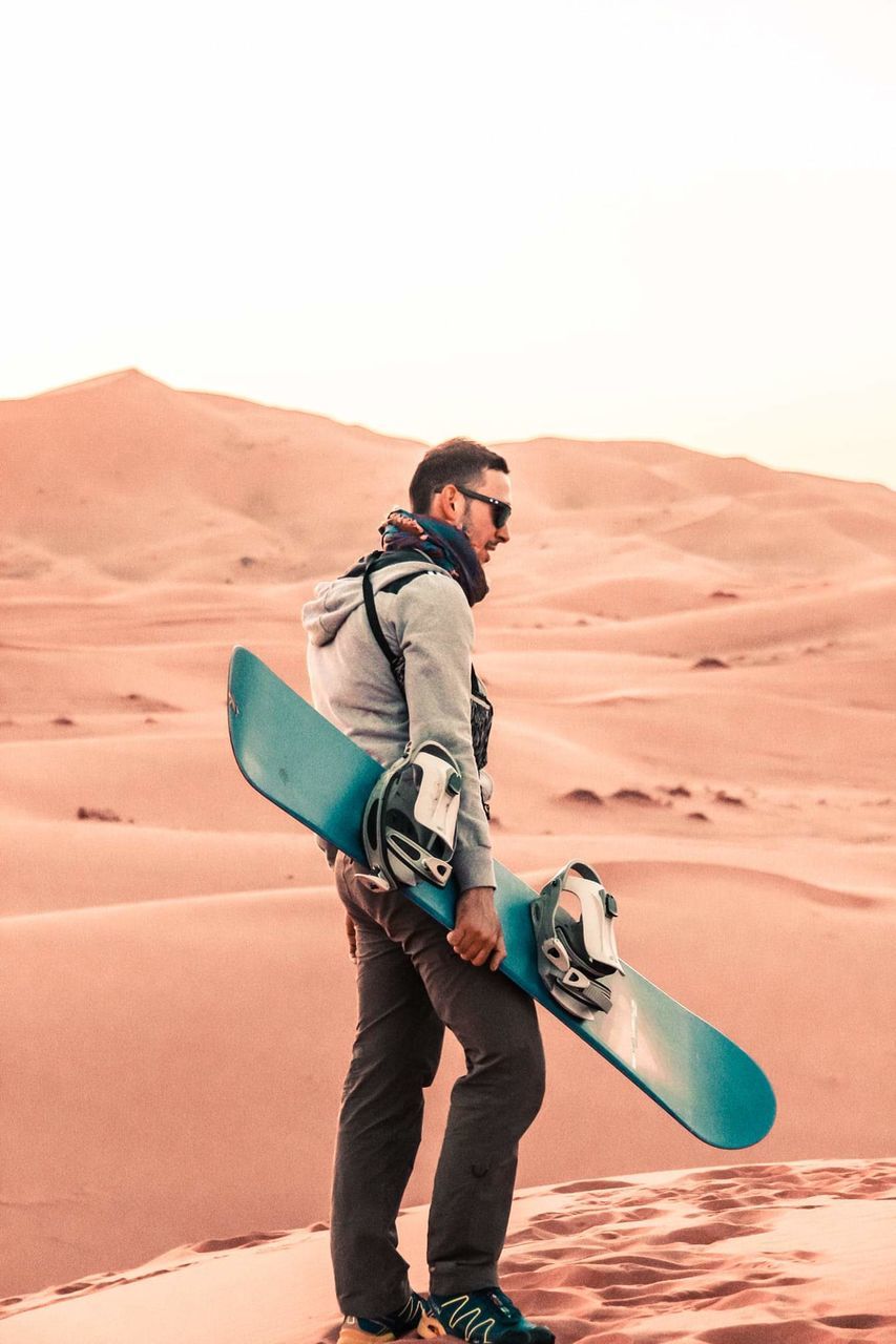 one person, desert, sky, sand, land, leisure activity, real people, lifestyles, sand dune, full length, scenics - nature, arid climate, climate, standing, nature, beauty in nature, young men, men, adventure, outdoors