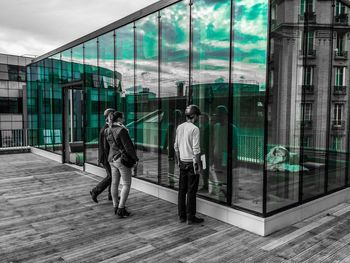 Rear view of people walking on glass window