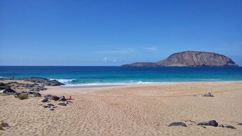 Scenic view of beach against clear blue sky