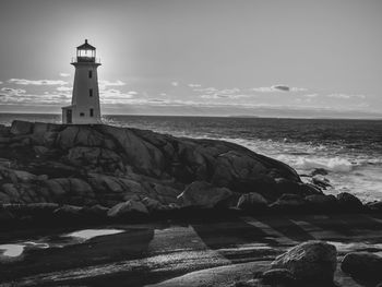 Lighthouse by sea against sky