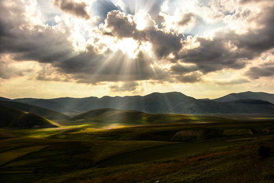 Sunlight streaming through clouds over landscape