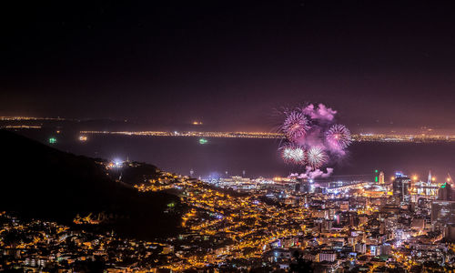 Aerial shot of illuminated cityscape against sea