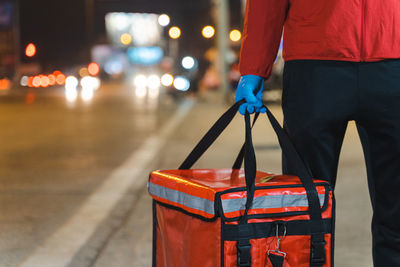 Midsection of person standing on illuminated street at night