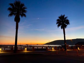 Silhouette palm trees at beach against sky at sunset