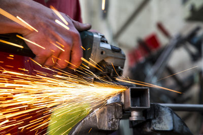 Midsection man grinding metal in factory