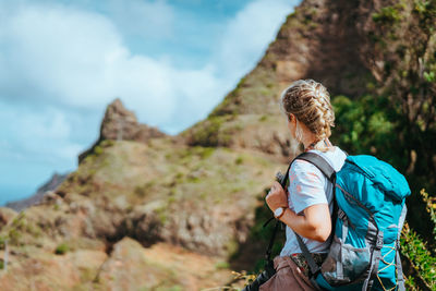 Woman with camera and backpack in front of the arid fins of rocks on santo antao island, cabo verde