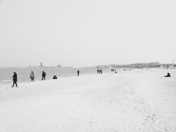 People on beach against clear sky during winter