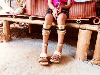 Low section of girl sitting on wood