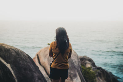 Rear view of man looking at sea against sky