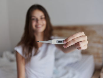 Woman checking temperature while sitting at home