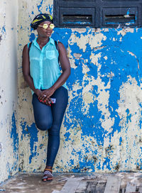 Full length of woman standing against blue wall